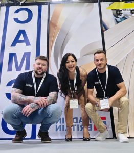 Three exhibitors posing in front of a stand graphic at a trade exhibition