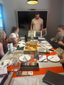Presenter speaking to the group, with samples and lunch on the table, at the FKM lunch and learn
